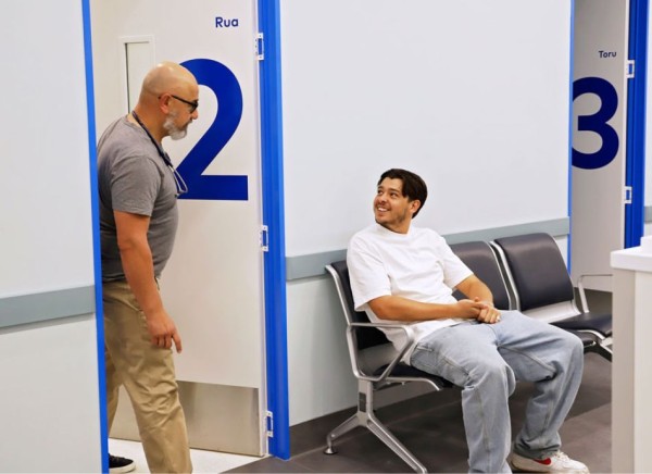 Healthcare professional calls a young man in for his appointment