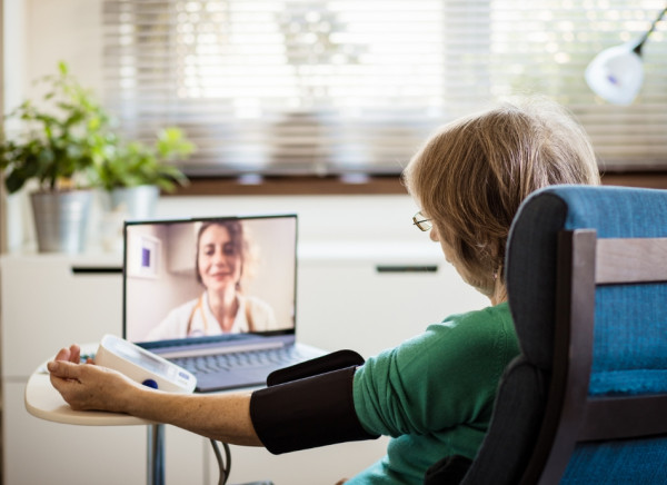 Woman taking her blood pressure in telehealth consultation