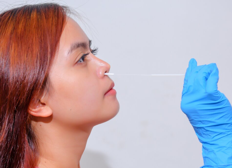 Young woman wearing gloves does nasal swab