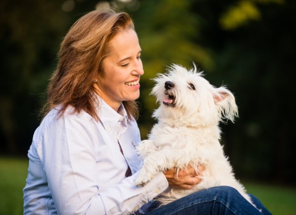 Woman cuddling small white dog