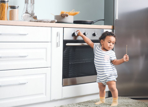 Child playing with dials on stove