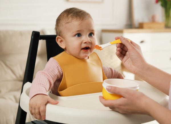 Baby in highchair being fed pureed food