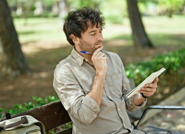 Young man sitting on bench reviewing list