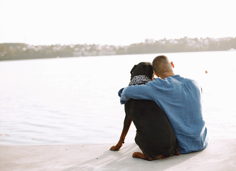 Young man with dog looking at sea