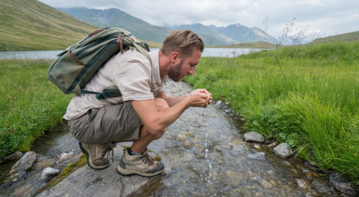 Man drinking water from stream 