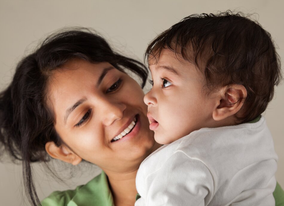 Young Asian woman looks lovingly at her baby