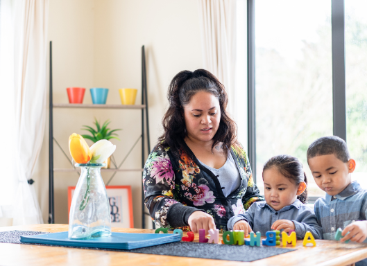 Māori wahine with two tamariki playing with blocks