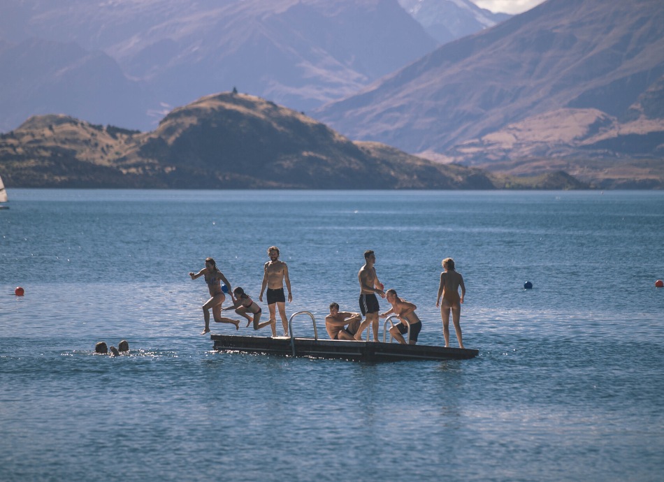 Swimmers jumping off a pontoon into Lake Wanaka New Zealand